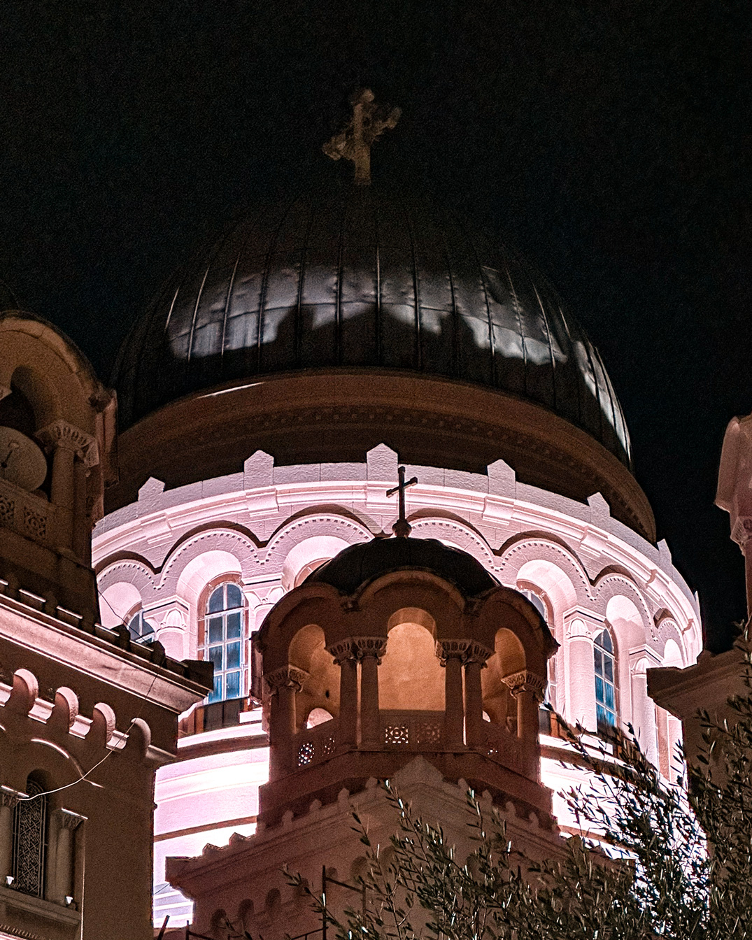 Illuminated church dome and arched windows against the night sky in Patras.