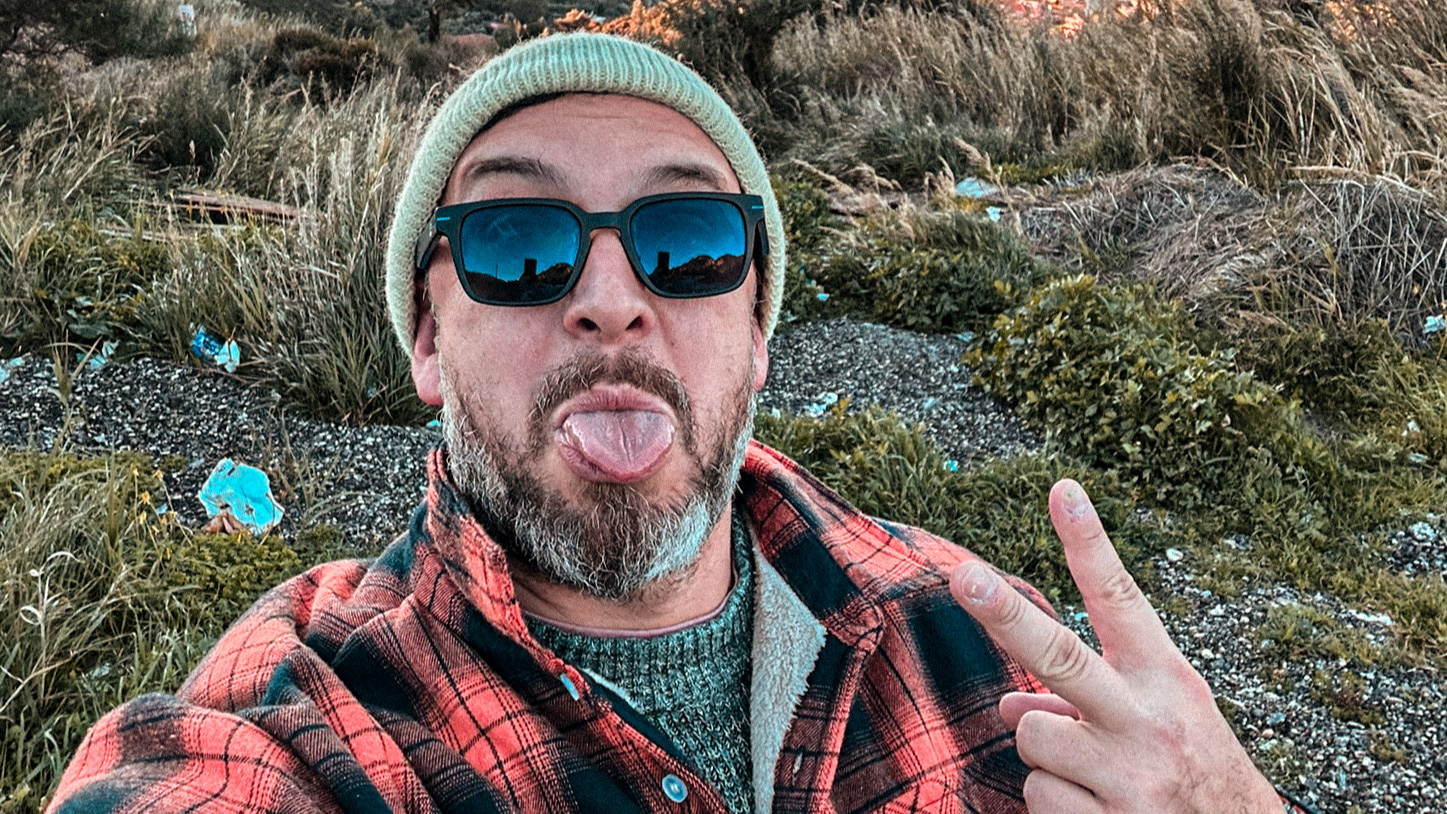 Self-portrait wearing a green beanie and sunglasses, making a peace sign on a hillside near Patras.