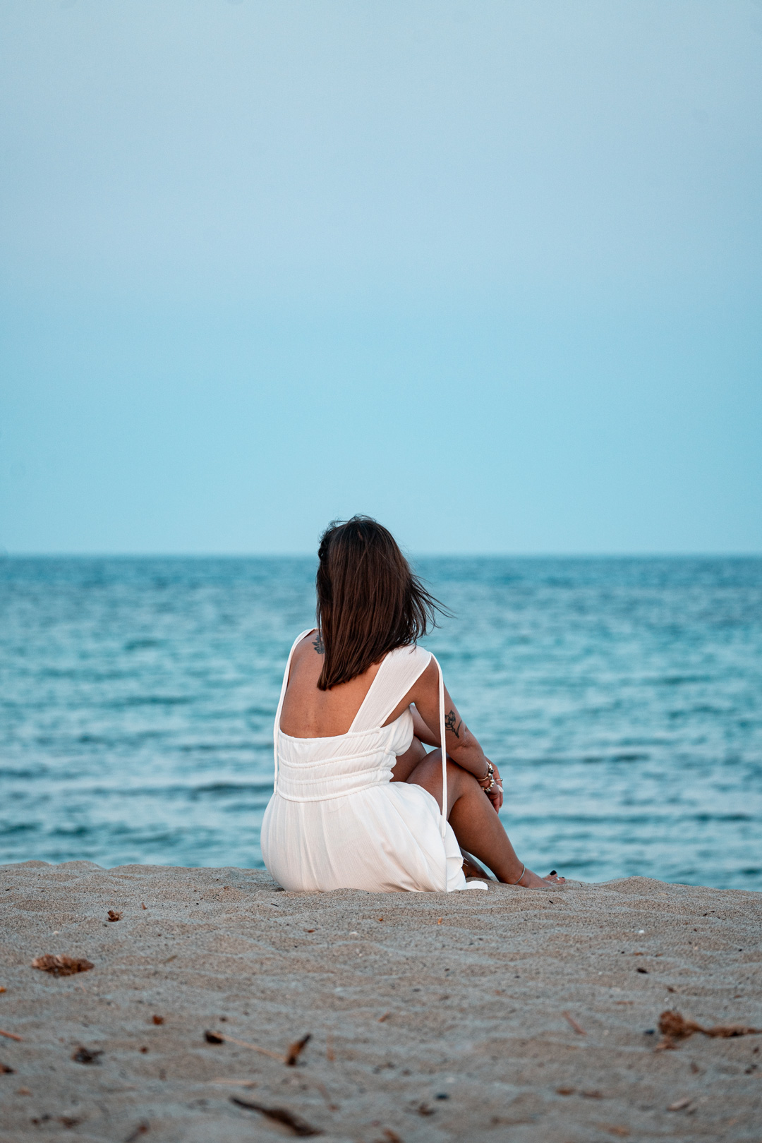 Eirini seated on the sand facing the sea at Possidi Cape.